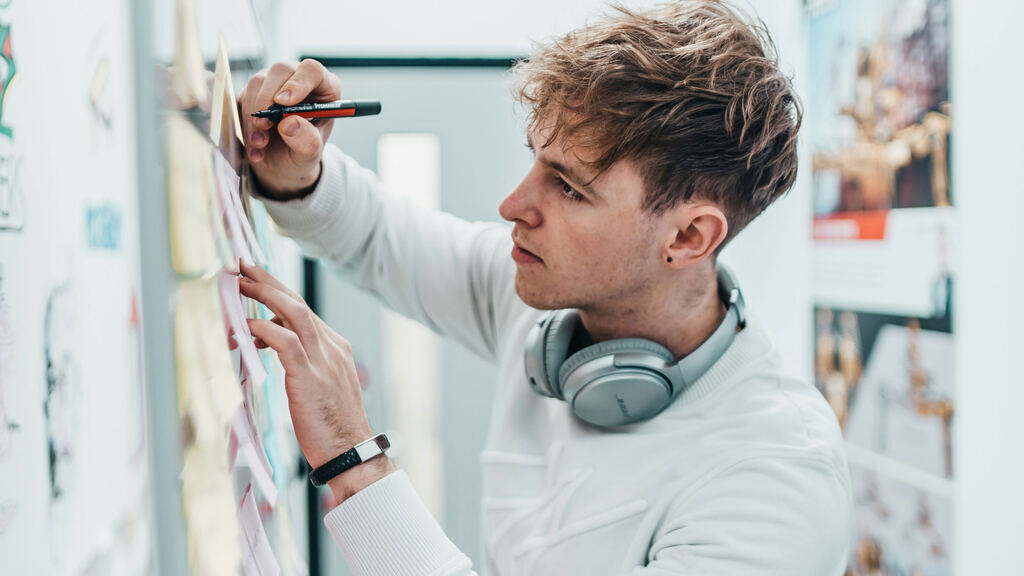 Focused professional deep in concentration writing on a whiteboard, locked into deep work